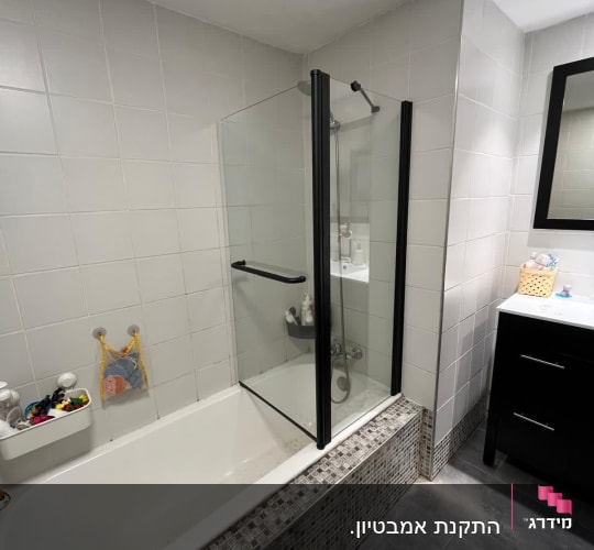 אמבטיה עם דלת זכוכית ומדף עם צעצועים